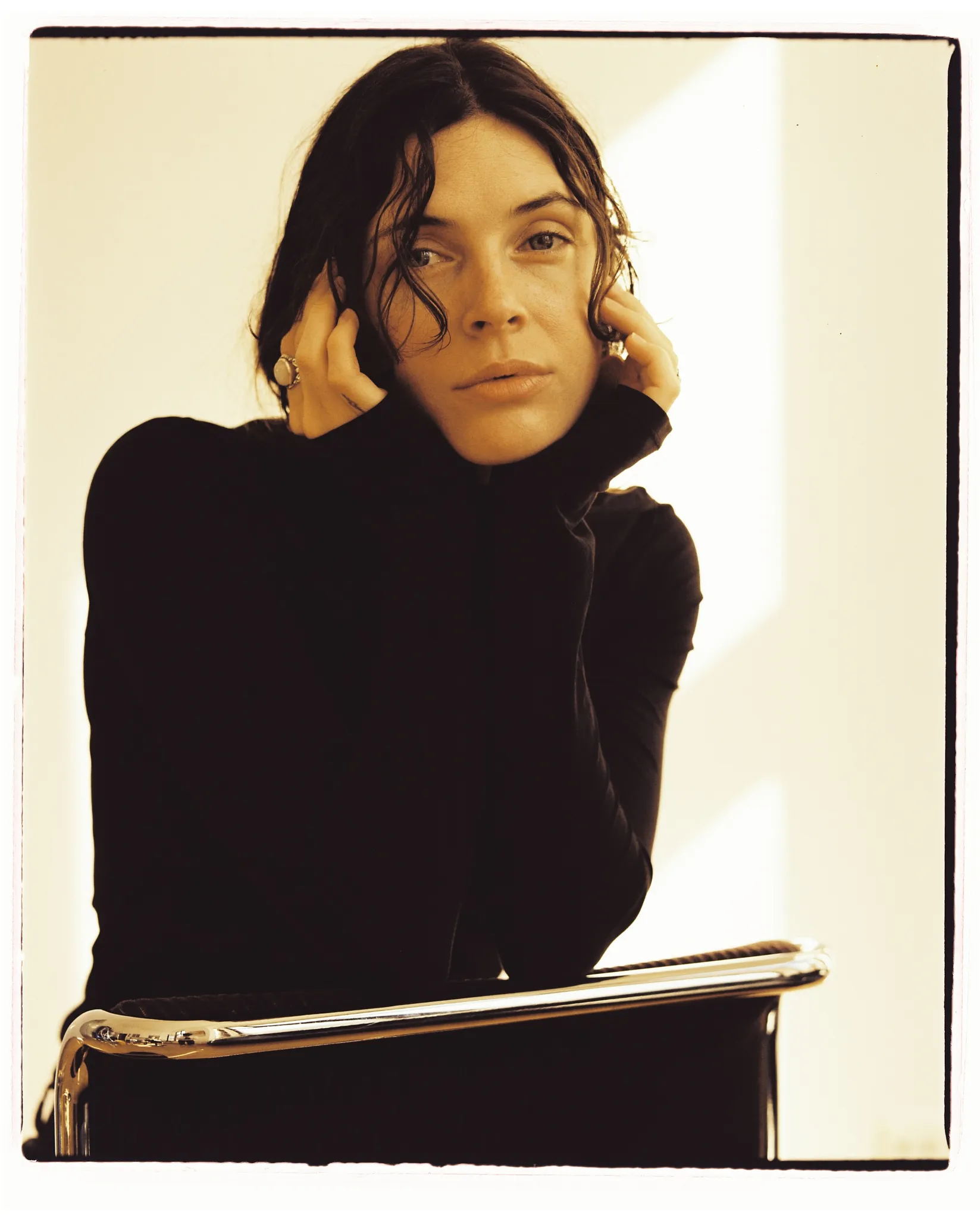 a color negative film photo of a female model looking at the camera. warm tones, lifted blacks with a film frame